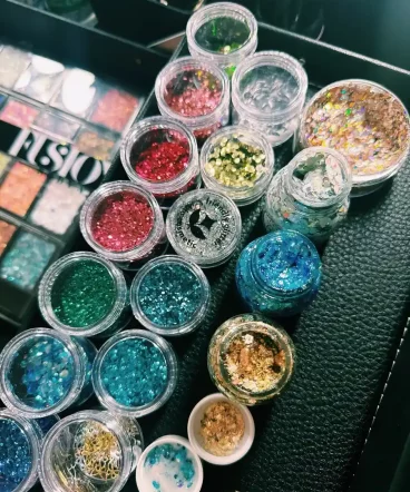 Ein rangezoomtes Bild des Schminkkoffers der Glitzerbar mit verschiedenen Glitzerdosen. Glitzerbar Erwachsene Glitzerbar Swifties Festival