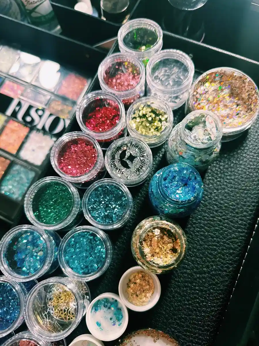 Ein rangezoomtes Bild des Schminkkoffers der Glitzerbar mit verschiedenen Glitzerdosen. Glitzerbar Erwachsene Glitzerbar Swifties Festival