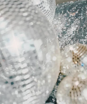Glitzernde Discokugeln und funkelnde Pailletten reflektieren das Licht in einer traumhaften Nahaufnahme.