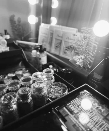 Nahaufnahme des Glitzerkoffers. Glitzer Schminkstation mit Glitzertiegeln, Make-up-Produkten und leuchtenden Spiegellichtern.